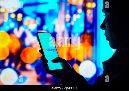 Brasilien. 31.. Mai 2022. In dieser Abbildung hält eine Frau mit Silhouetten ein Smartphone mit dem Coforge-Logo auf dem Bildschirm. (Bild: © Rafael Henrique/SOPA Images via ZUMA Press Wire) Stockfoto