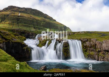 Kirkjufellsfoss. Fotografischer Hotspot mit Blick auf einen ikonischen Wasserfall und den markant geformten Mt. Kirkjufell, Island. Stockfoto