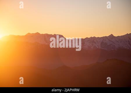 Die Sonne geht hinter den Bergen unter Stockfoto