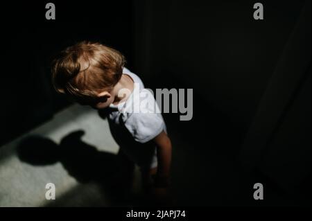 Dunkle High-Angle-Ansicht Porträt der traurigen anonymen kleinen Baby-Mädchen nach unten schauen. Stockfoto