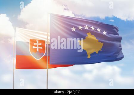 Sonniger blauer Himmel und Flaggen des kosovo und der slowakei Stockfoto