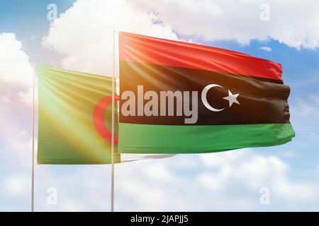 Sonniger blauer Himmel und Flaggen von libyen und algerien Stockfoto