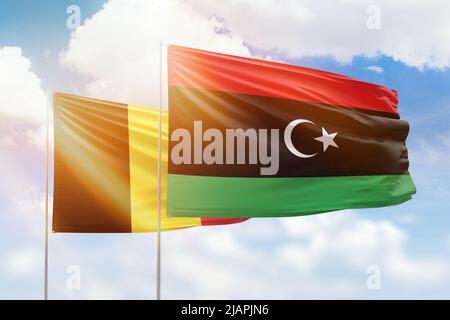 Sonniger blauer Himmel und Flaggen von libyen und belgien Stockfoto