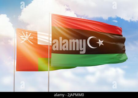 Sonniger blauer Himmel und Flaggen von libyen und oman Stockfoto