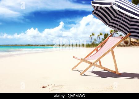 Liegestühle aus Holz am Sandstrand in der Nähe des Meeres. Hintergrund der Feiertage. Stockfoto