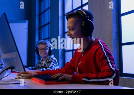 Junge Gamer Jungen mit Kopfhörern spielen Computer-Videospiel. Stockfoto