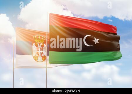 Sonniger blauer Himmel und Flaggen von libyen und serbien Stockfoto