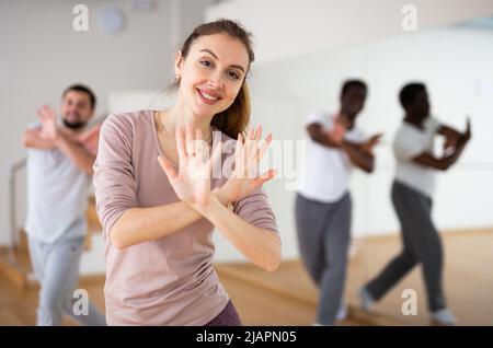 Fröhliche Frau, die während des Gruppentrainings aeroben Tanz tanzt Stockfoto