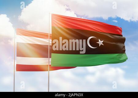 Sonniger blauer Himmel und Flaggen von libyen und thailand Stockfoto