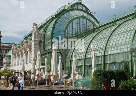 Café im Freien unter Sonnenschirmen vor einem Gewächshaus in Wien. Stockfoto