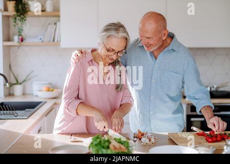 Glückliches Seniorenpaar, das zu Hause zusammen kocht. Stockfoto