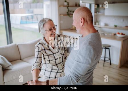 Fröhliches Seniorenpaar, das zu Hause zusammen tanzt. Stockfoto