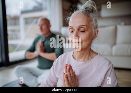Seniorenpaar macht zu Hause gemeinsam Entspannungsübungen. Stockfoto