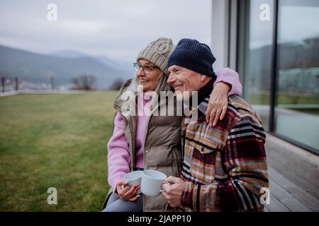 Ein glückliches Seniorenpaar sitzt auf der Terrasse und trinkt gemeinsam Kaffee. Stockfoto