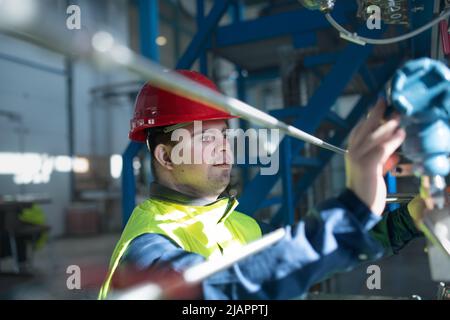 Junger Mann mit Down-Syndrom arbeitet in der industriellen Fabrik, soziale Integration Konzept. Stockfoto