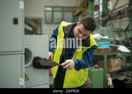 Junger Mann mit Down-Syndrom arbeitet in der industriellen Fabrik, soziale Integration Konzept. Stockfoto