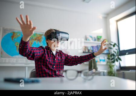 Neugieriger Schüler mit Virtual-Reality-Brille in der Schule im Informatikunterricht Stockfoto