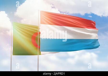 Sonniger blauer Himmel und Flaggen von luxemburg und algerien Stockfoto