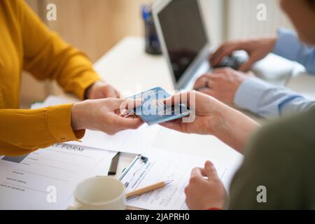 Freiwillige Helferinnen von Frauen und Männern, die der ukrainischen Frau beim Ausfüllen von Formularen im Asylzentrum helfen. Stockfoto