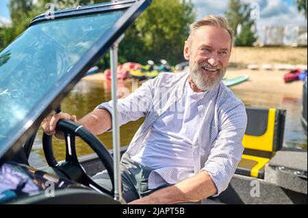 Ein bärtig lächelnder reifer Mann am Lenkrad Stockfoto