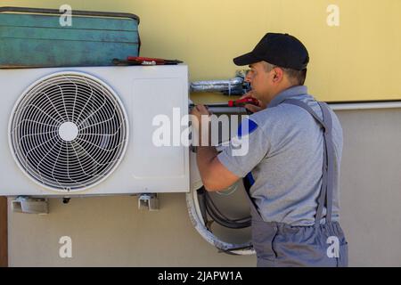 Bild eines Klempners mit Werkzeugen, die eine Klimaanlage in einem Haus installieren. Hinweis auf die bevorstehende Hitze Stockfoto