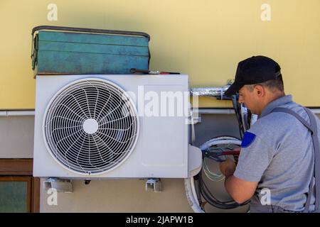 Foto eines Installators, der den Motor einer Klimaanlage zusammenführt und gewartet. Do-it-yourself-Arbeit Stockfoto