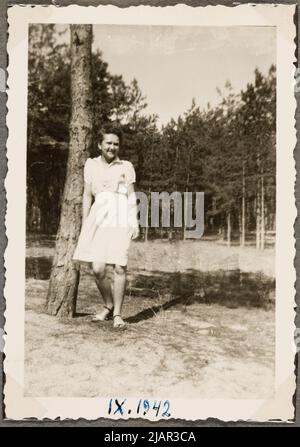 Eine junge Frau, die auf einer Waldlichtung auf einem Baumstamm steht. Kreis der Familie Stachiewicz Stockfoto
