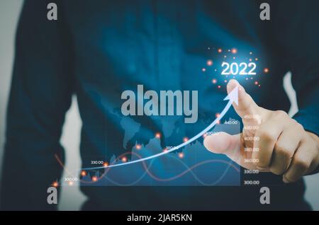 Geschäftsmann berührt Pfeile und Diagramme auf einem virtuellen Bildschirm. Financial Business Planning 2022 Marketing Goals Konzept. Stockfoto