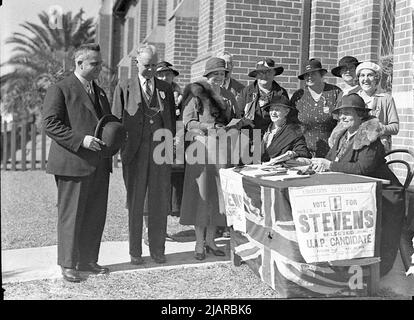 Ein Foto von Premier Bertram Stevens (links) und Männern und Frauen bei einem Wahllokal in Croydon für die Landtagswahl in New South Wales. Ca. 1935 Stockfoto