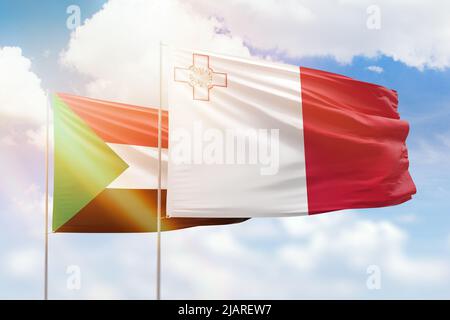 Sonniger blauer Himmel und Flaggen von malta und sudan Stockfoto