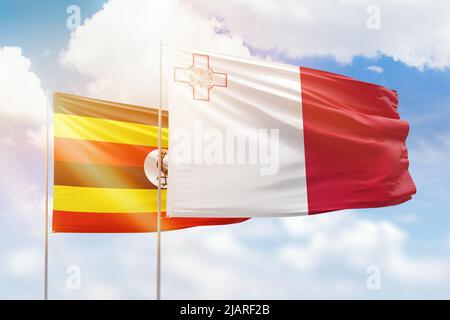 Sonniger blauer Himmel und Flaggen von malta und uganda Stockfoto