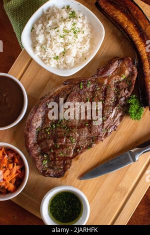 Angus Rindfleisch Grill mit 3 Seiten und Reissauce Holztisch mit einem Messer Stockfoto