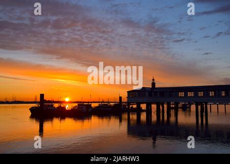 01/06/2022 Gravesend UK ein irisierender Sonnenaufgang und -Untergang über dem Royal Terrace Pier, der sich am ersten Tag in den ruhigen Gewässern der Themse widerspiegelt Stockfoto