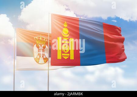 Sonniger blauer Himmel und Flaggen der mongolei und serbiens Stockfoto