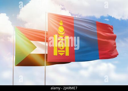 Sonniger blauer Himmel und Flaggen der mongolei und des sudan Stockfoto