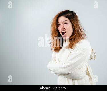 Nahaufnahme Porträt einer verrückten Frau in Zwangsjacke auf weißem Hintergrund. Stockfoto