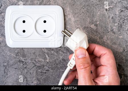 Männliche Hand steckt Stecker in die Steckdose, Nahaufnahme Stockfoto