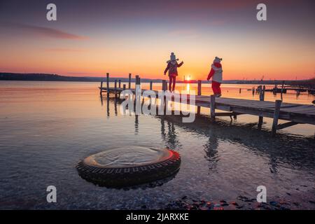 Schöne Landschaft von alten Pier für Fischerboote und Ufer während des Sonnenuntergangs über dem See Stockfoto