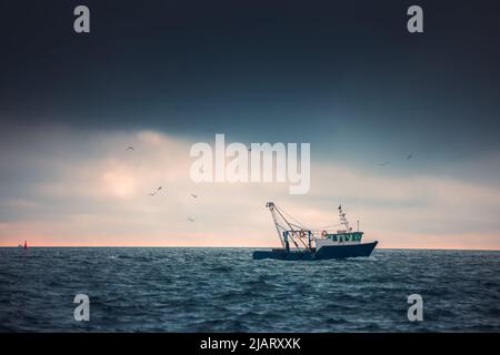 Fischerboot und Fischer im Meer, nebeliger Morgen über das Wasser. Stockfoto