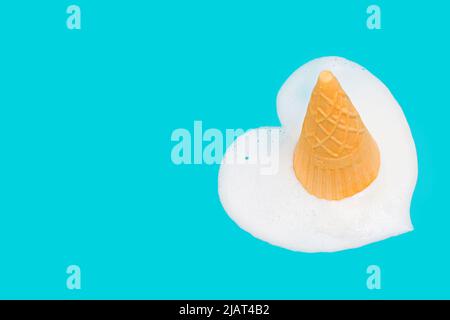 Herzförmige Pfütze aus geschmolzenem Waffeleisen-Eis auf blauem Hintergrund. Stockfoto
