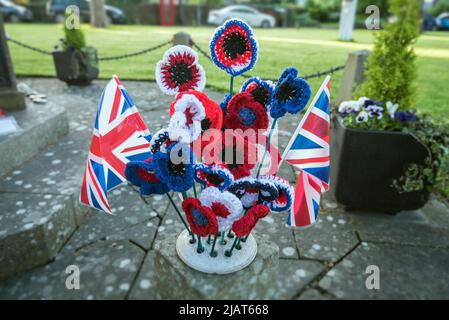 Long Preston Village feiert das Platin-Jubiläum von Königin Elizabeth 11 mit rot-weißen und blauen Gewerkschaftsjacken und gestrickten Blumen auf dem Kriegsdenkmal. Stockfoto