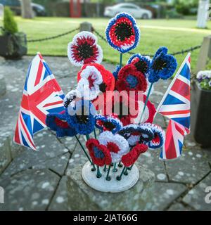 Long Preston Village feiert das Platin-Jubiläum von Königin Elizabeth 11 mit rot-weißen und blauen Gewerkschaftsjacken und gestrickten Blumen auf dem Kriegsdenkmal. Stockfoto