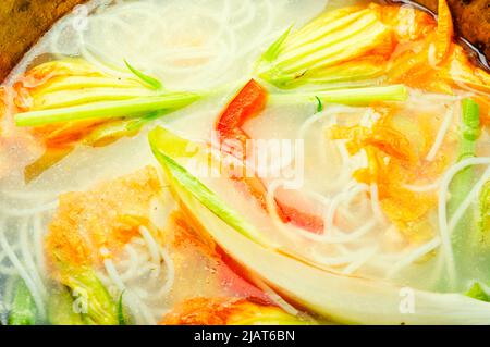 Suppe mit Reisnudeln und Knödeln in Kürbisblüten Stockfoto