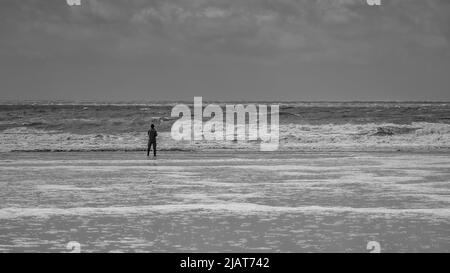 Ein eineiiger Fischer, vor dem Meer, an einem stürmischen Tag. Stockfoto