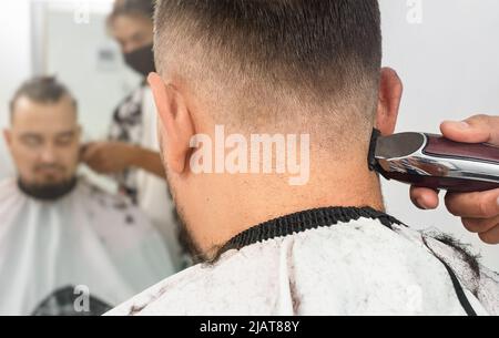 Friseur schneidet einem Mann in einem Friseursalon mit einem Rasiermesser die Haare Stockfoto