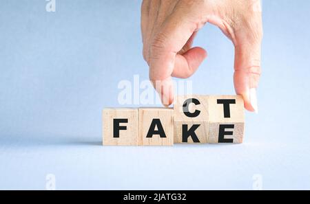 Finger, die Holzwürfel drehen, blockieren, von Fakten bis zu falschen Formulierungen. Stockfoto