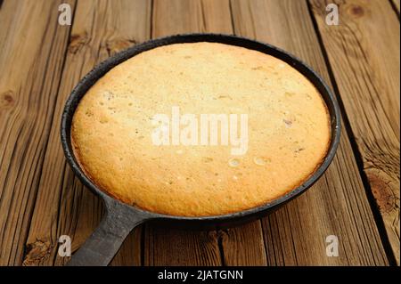 Frisch gebackene leckere gebräunte Torte in gusseiserner Pfanne auf Holztisch horizontal Stockfoto