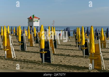 Rettungsschwimmer-Turm und Linien von leuchtend gelben und dunkelblauen Schirmen und Liegestühlen am Ostia-Strand, Rom, Italien, Europa, Europäische Union, EU Stockfoto