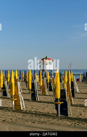 Rettungsschwimmer-Turm und Linien von leuchtend gelben und dunkelblauen Schirmen und Liegestühlen am Ostia-Strand, Rom, Italien, Europa, Europäische Union, EU Stockfoto