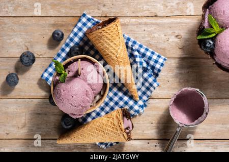 Heidelbeer-Eisschaufeln mit Waffel auf Holztisch Stockfoto